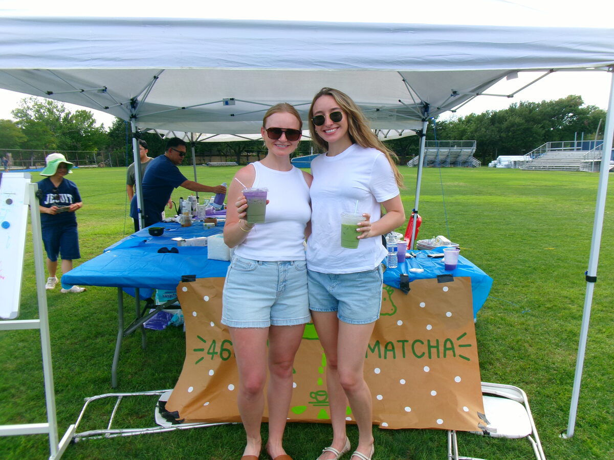 Two customers with drinks in front of the banner